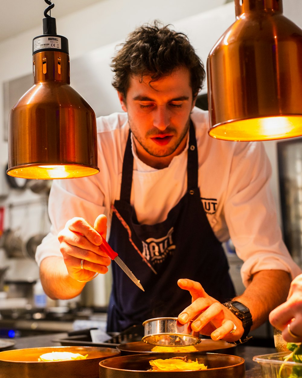 Head chef working at the pass under warm pendant lights