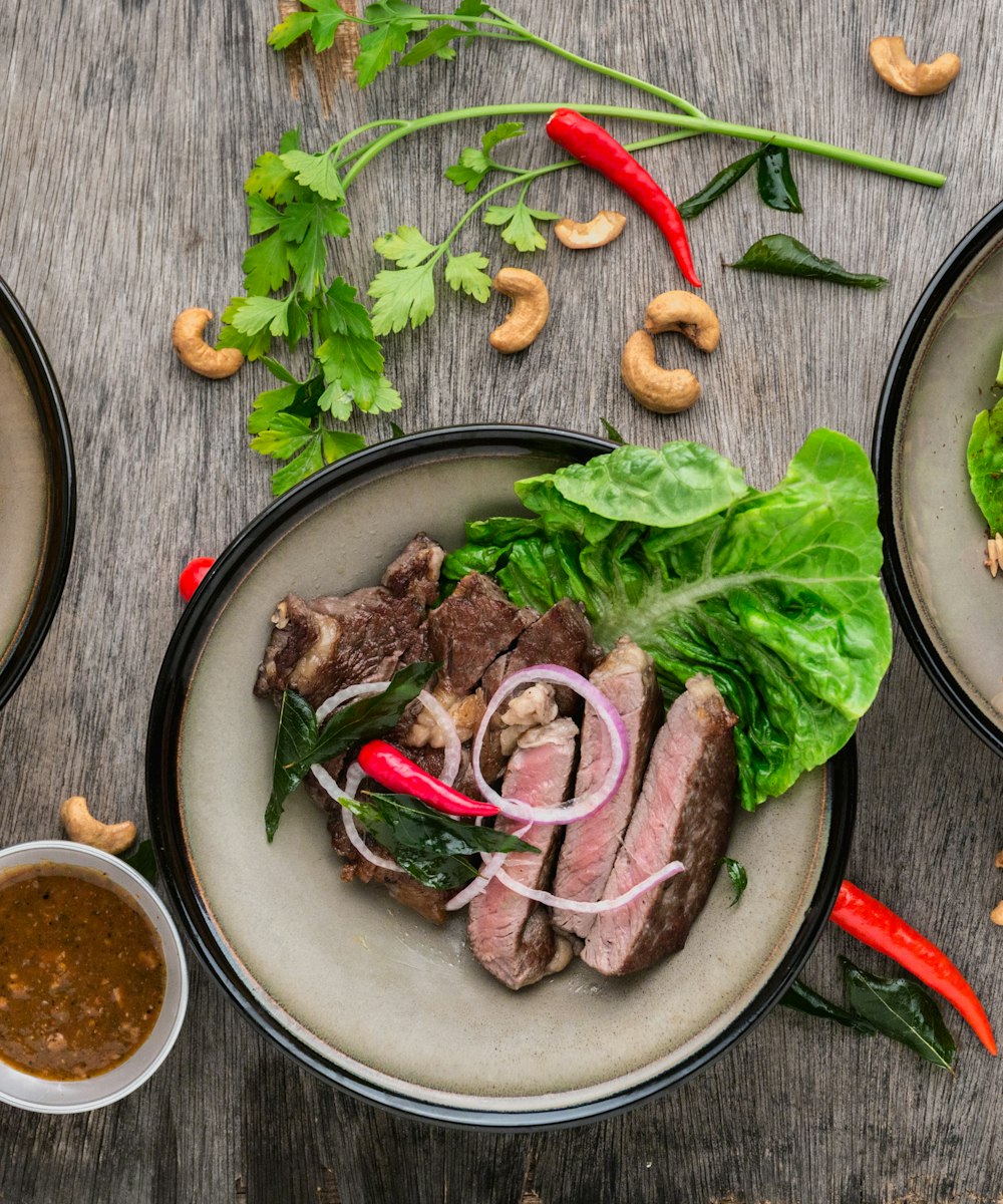 Sliced pink-cooked steak on a sharing board with greens