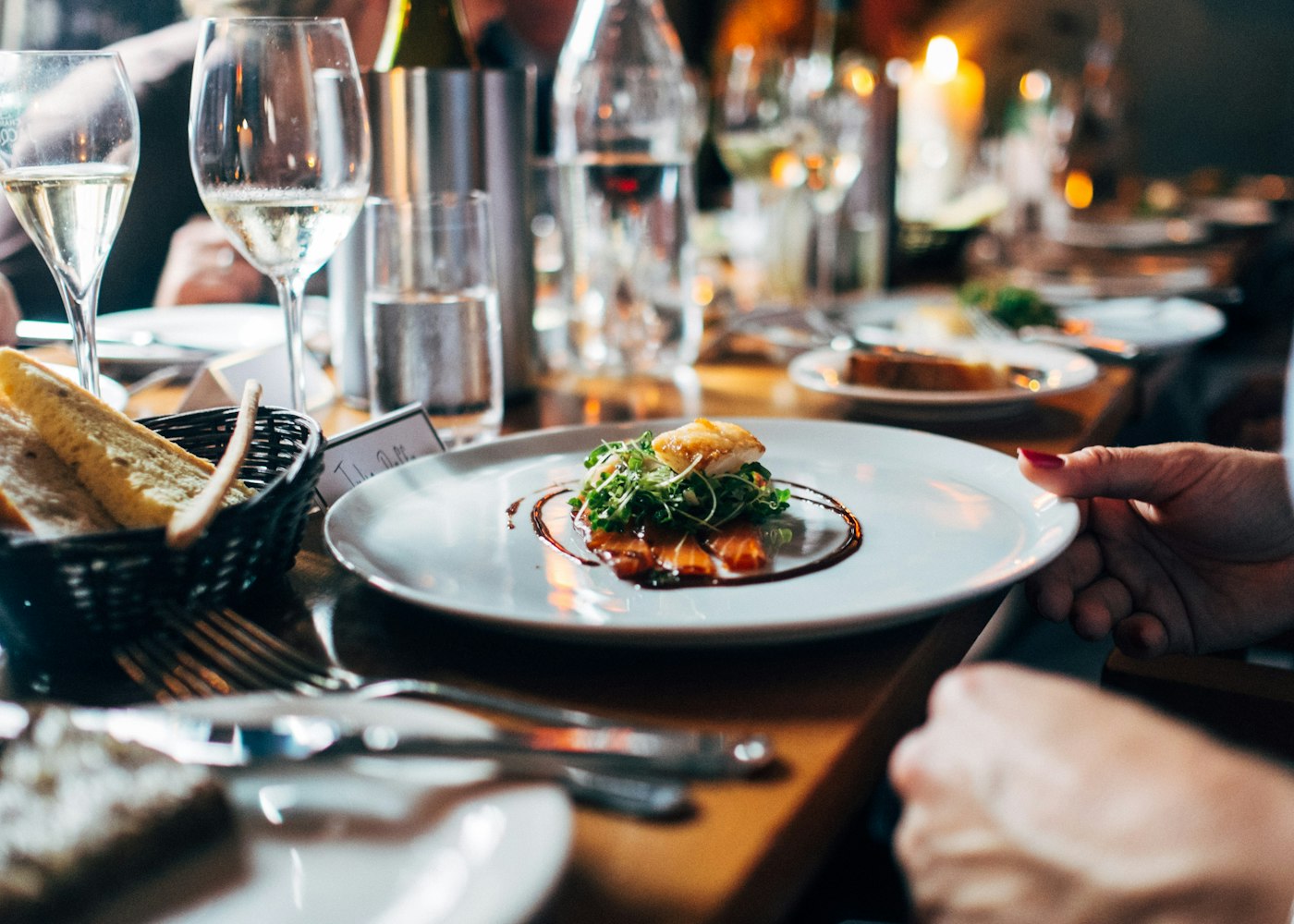 A candle-lit table set for dinner with diners beyond